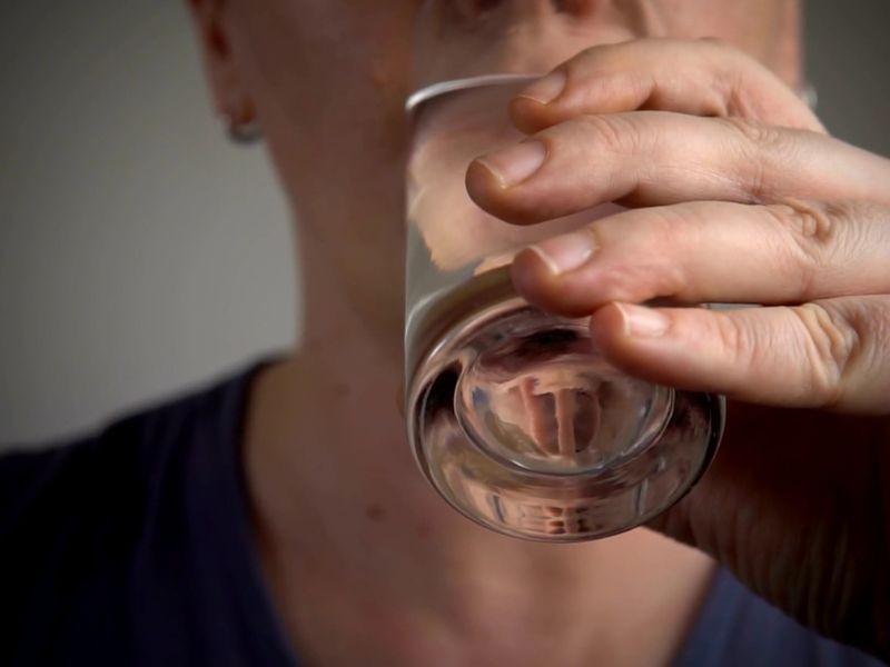 Žena u crnoj majici pije vodu i staklene čase