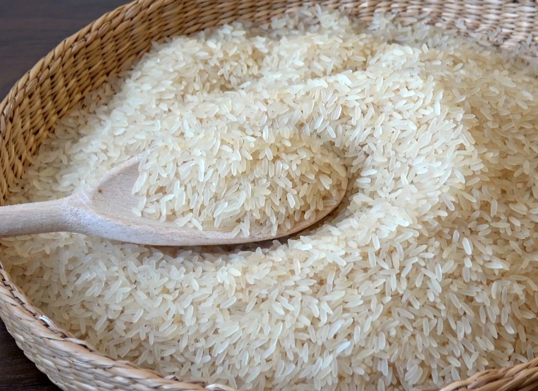 pirinač u drvenoj činiji sa drvenom kašikom